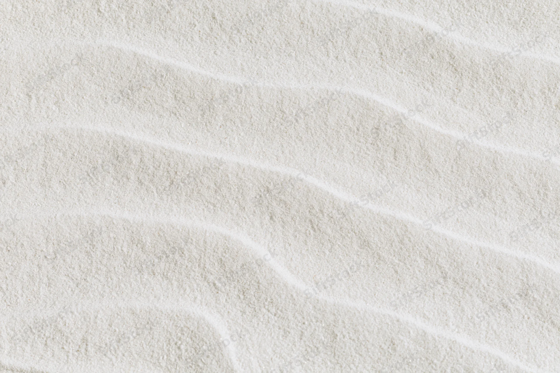 Close-up of fine white sand with smooth raked wave patterns in a flat lay arrangement