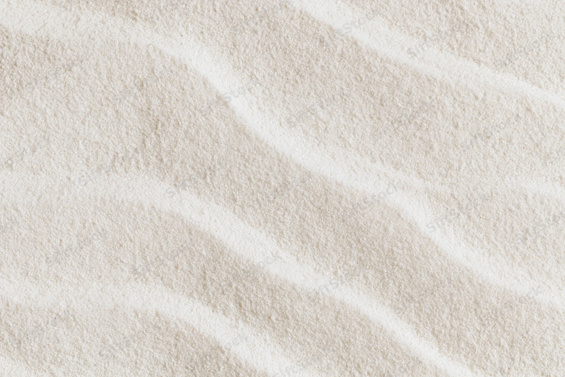 Close-up of raked white sand forming smooth wave patterns in a flat lay arrangement
