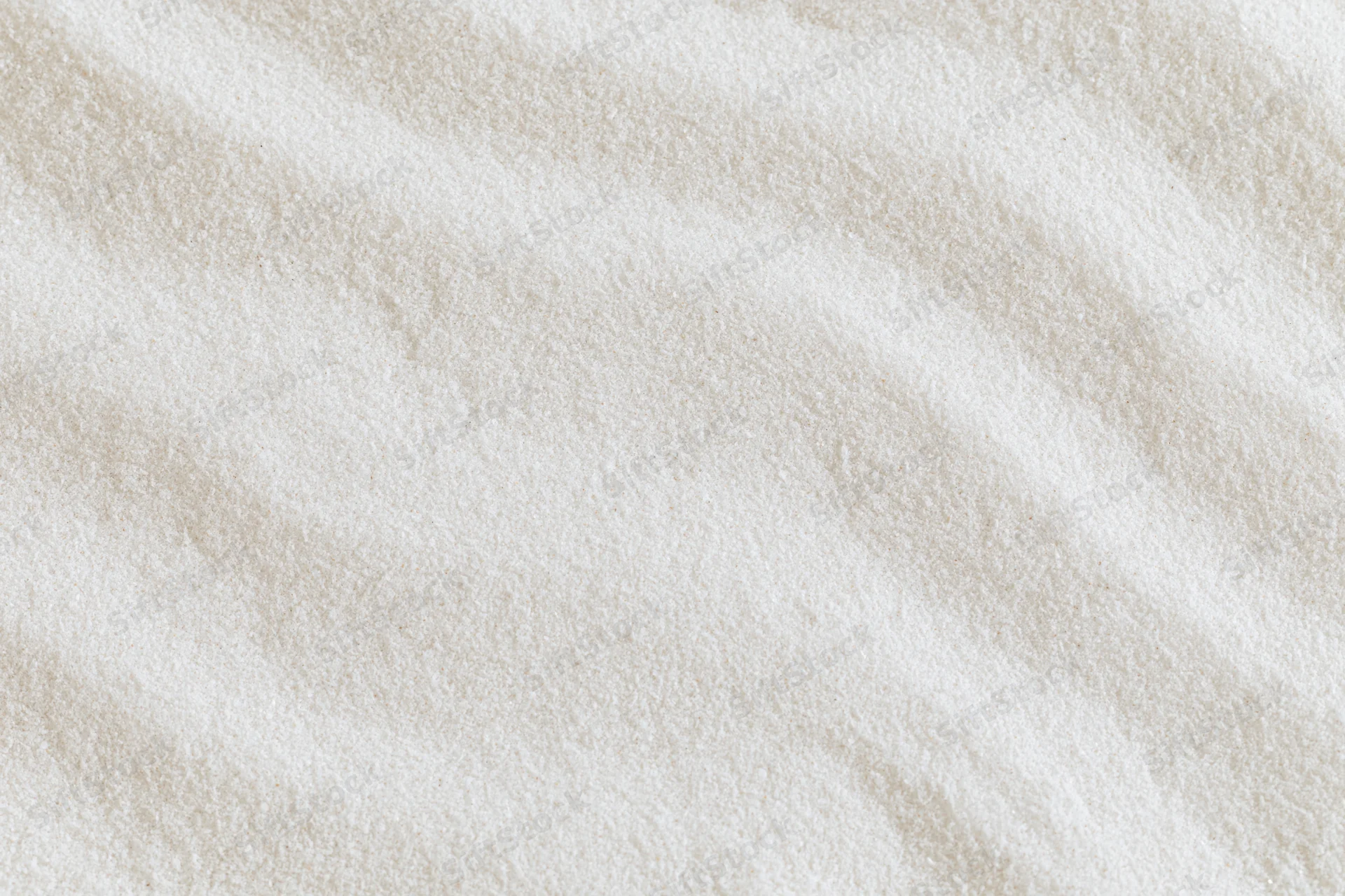 Close-up of fine white sand with smooth raked wave patterns in a flat lay arrangement