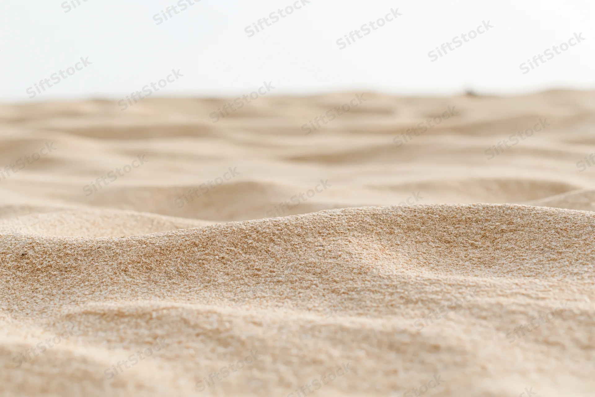 Closeup of dry beach sand with rippled texture under bright light