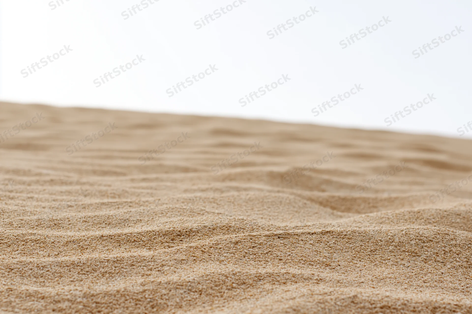 Close-up of dry beach sand with ripples and texture filling the frame against a white background