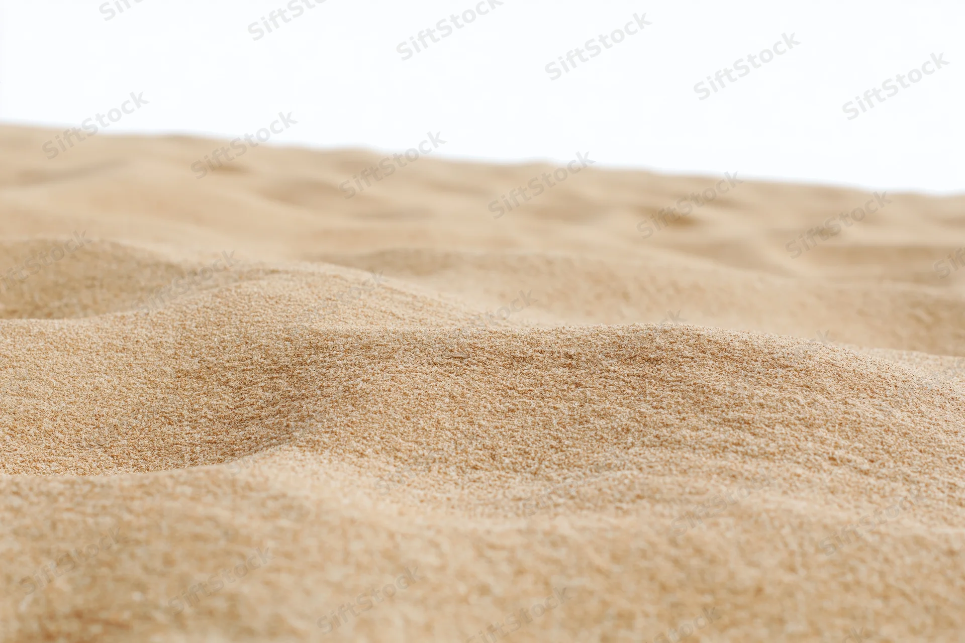 Close-up of dry beach sand with rippled texture against white background