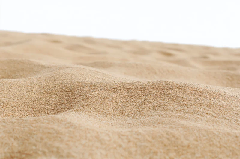 Close-up of dry beach sand with rippled texture against white background