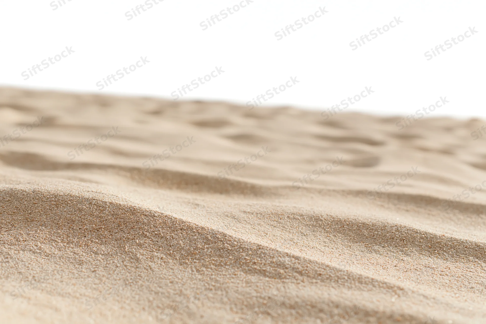 Close-up of rippled dry beach sand at ground level against white background
