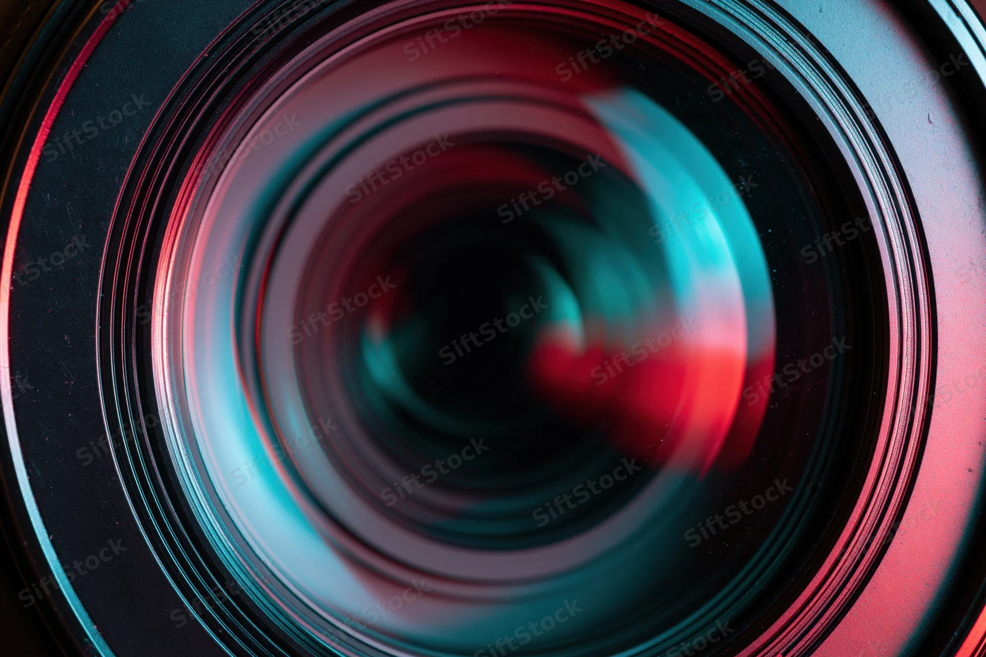 Close-up of a camera lens front element showing concentric glass rings with red and blue reflections