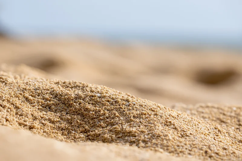 Close-up of mounded beach sand with blurred ocean background
