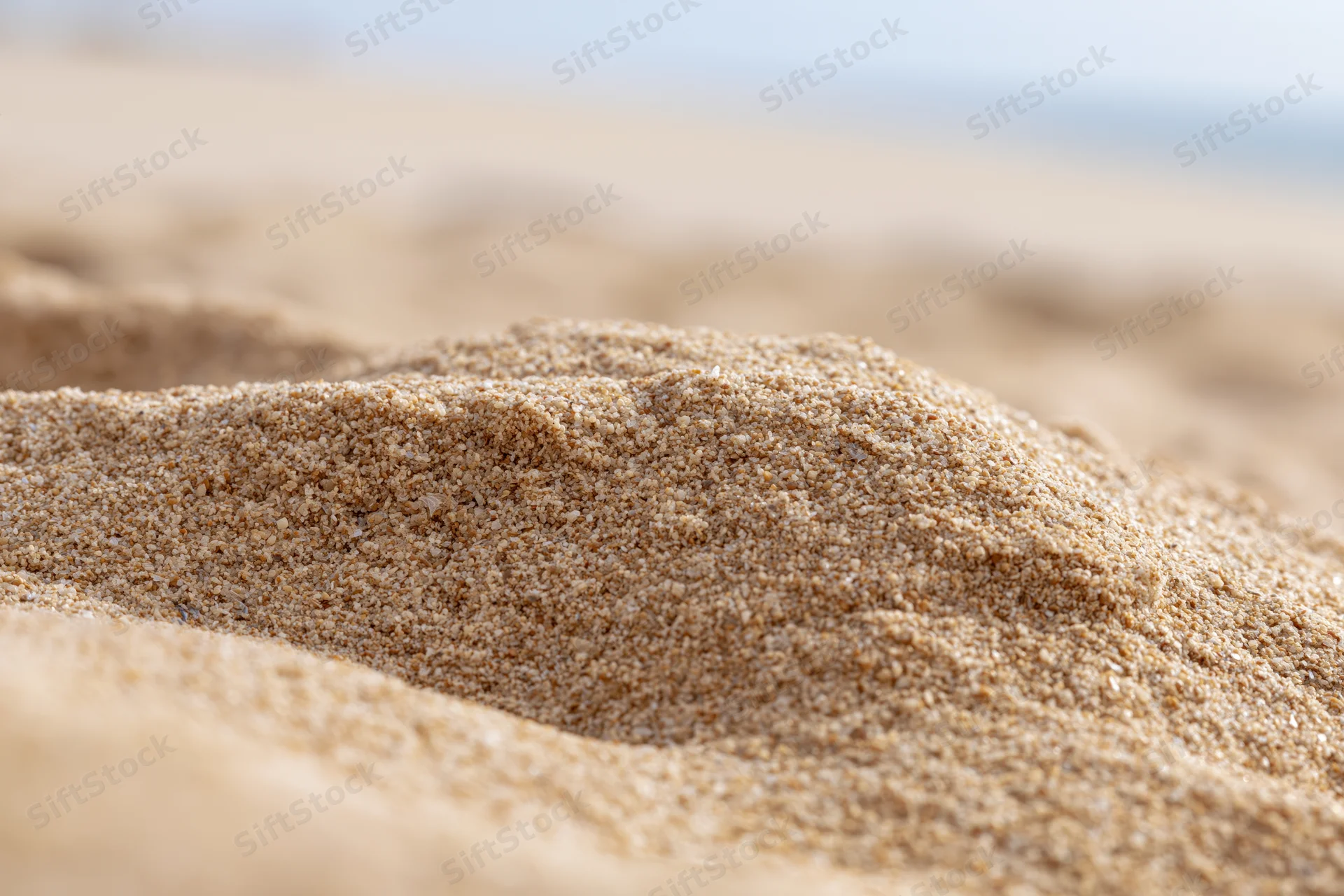 Close-up of mounded dry beach sand with shallow depth of field and blurred background