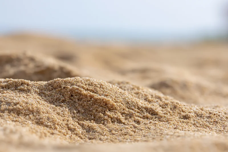 Close-up of dry beach sand mounded in the foreground with blurred background