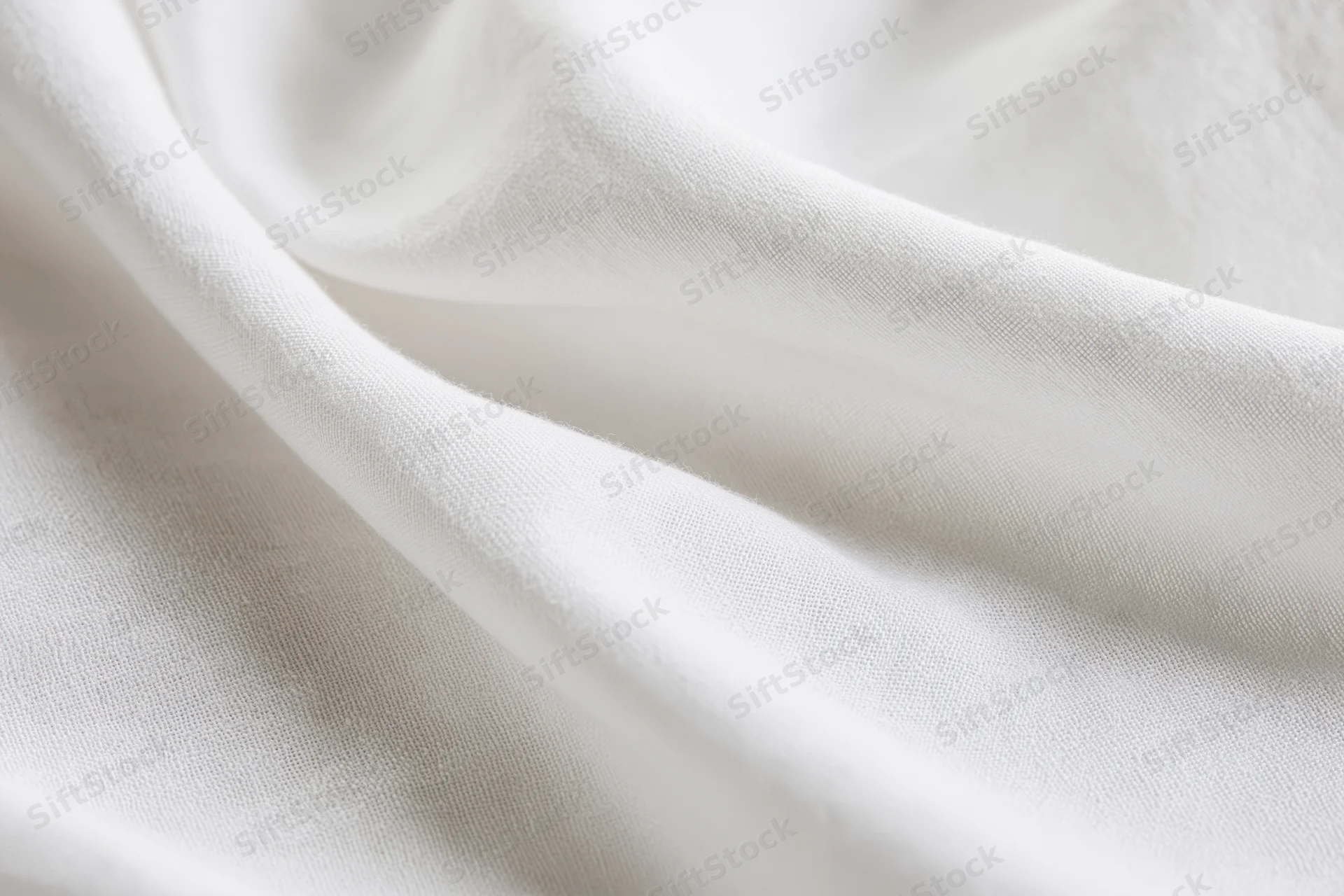 Close-up of white fabric with soft diagonal folds showing texture and weave