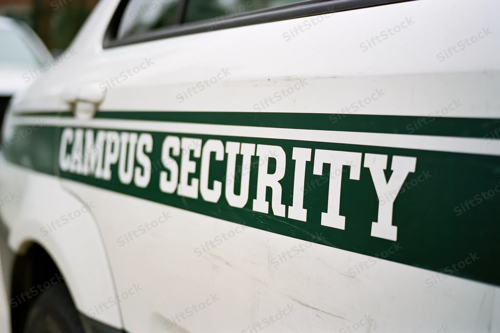 Close-up of white campus security vehicle door panel with green lettering