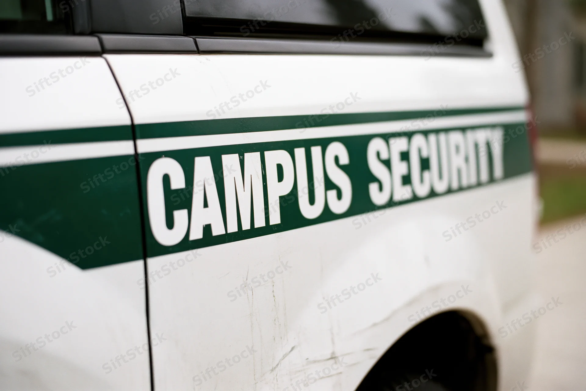 Close-up of white campus security vehicle door with green stripe and lettering