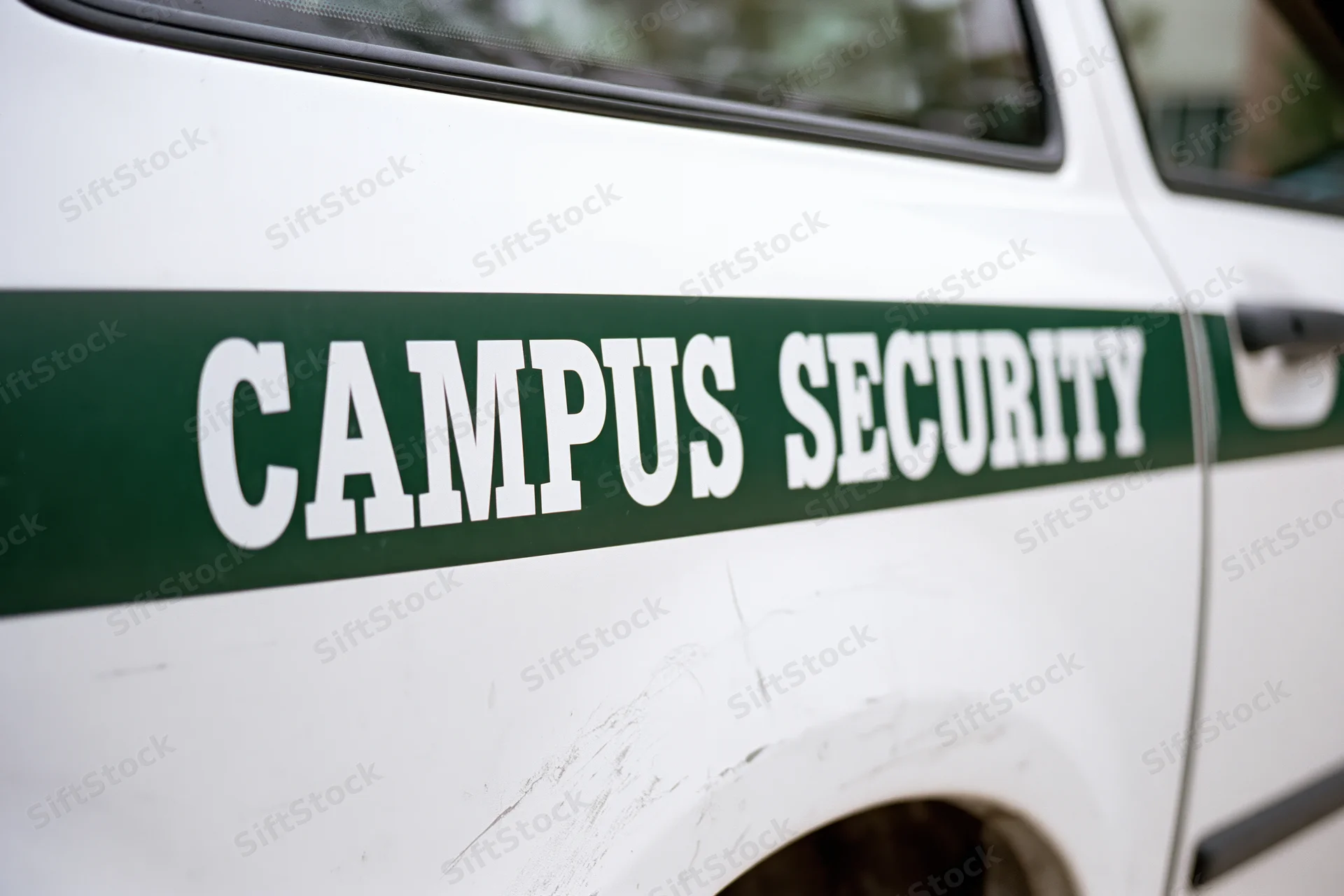 Close-up of white campus security vehicle door with green stripe and lettering