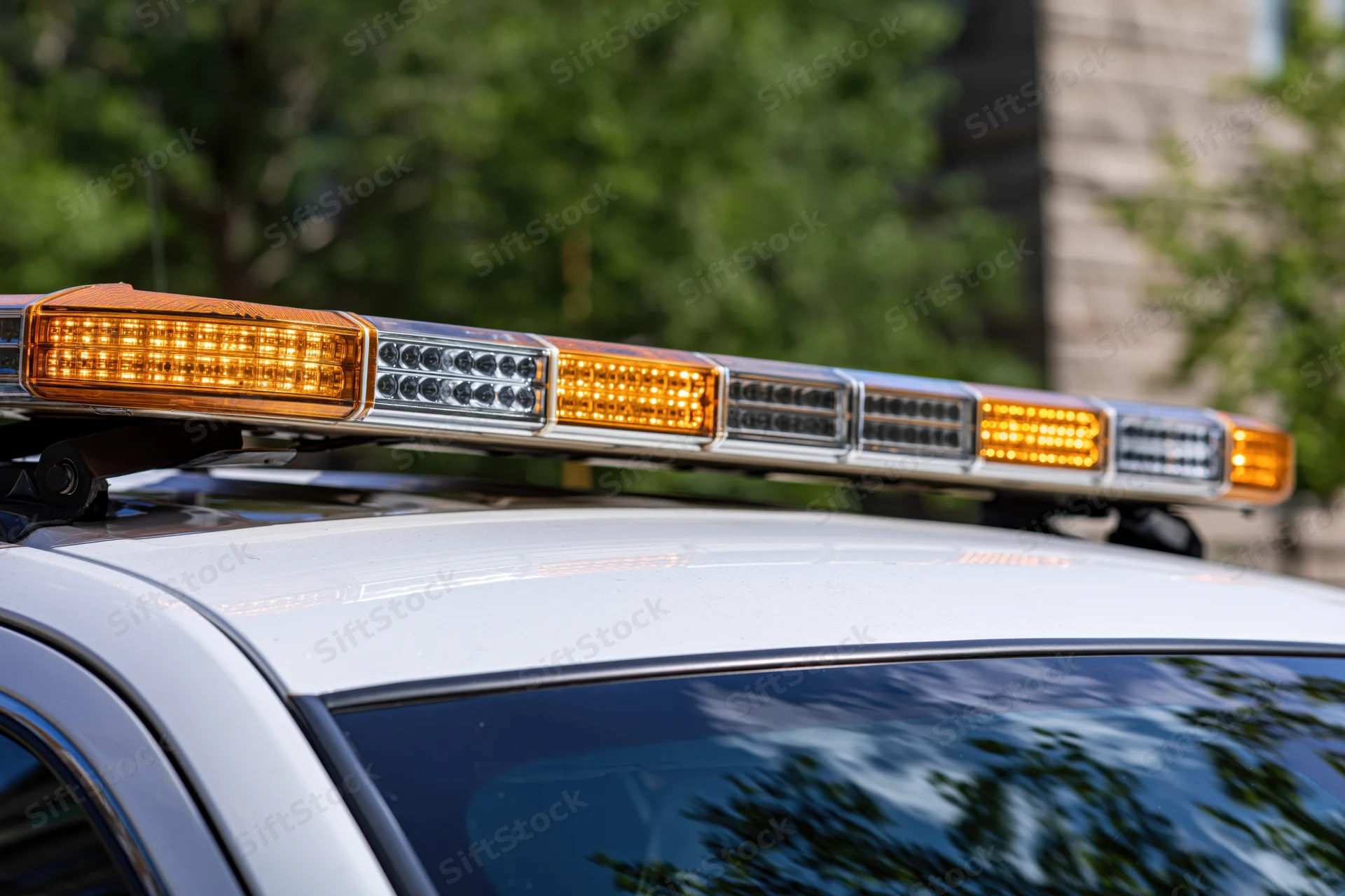 Amber and white led light bar mounted on top of a police vehicle outdoors