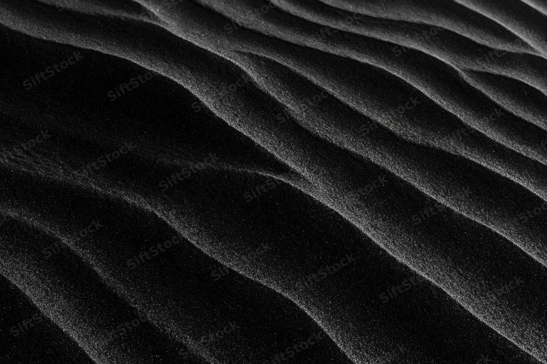 Close-up of rippled black volcanic sand dunes shaped by wind