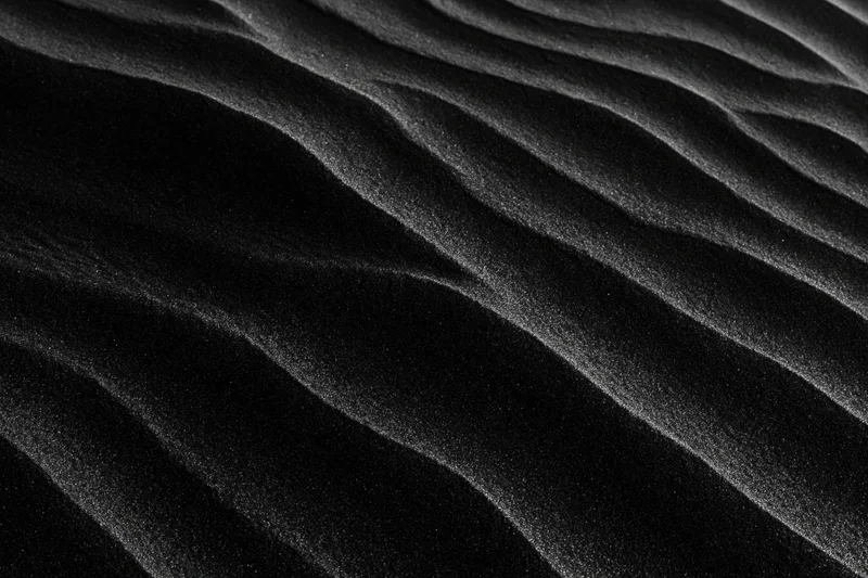 Close-up of rippled black volcanic sand dunes shaped by wind