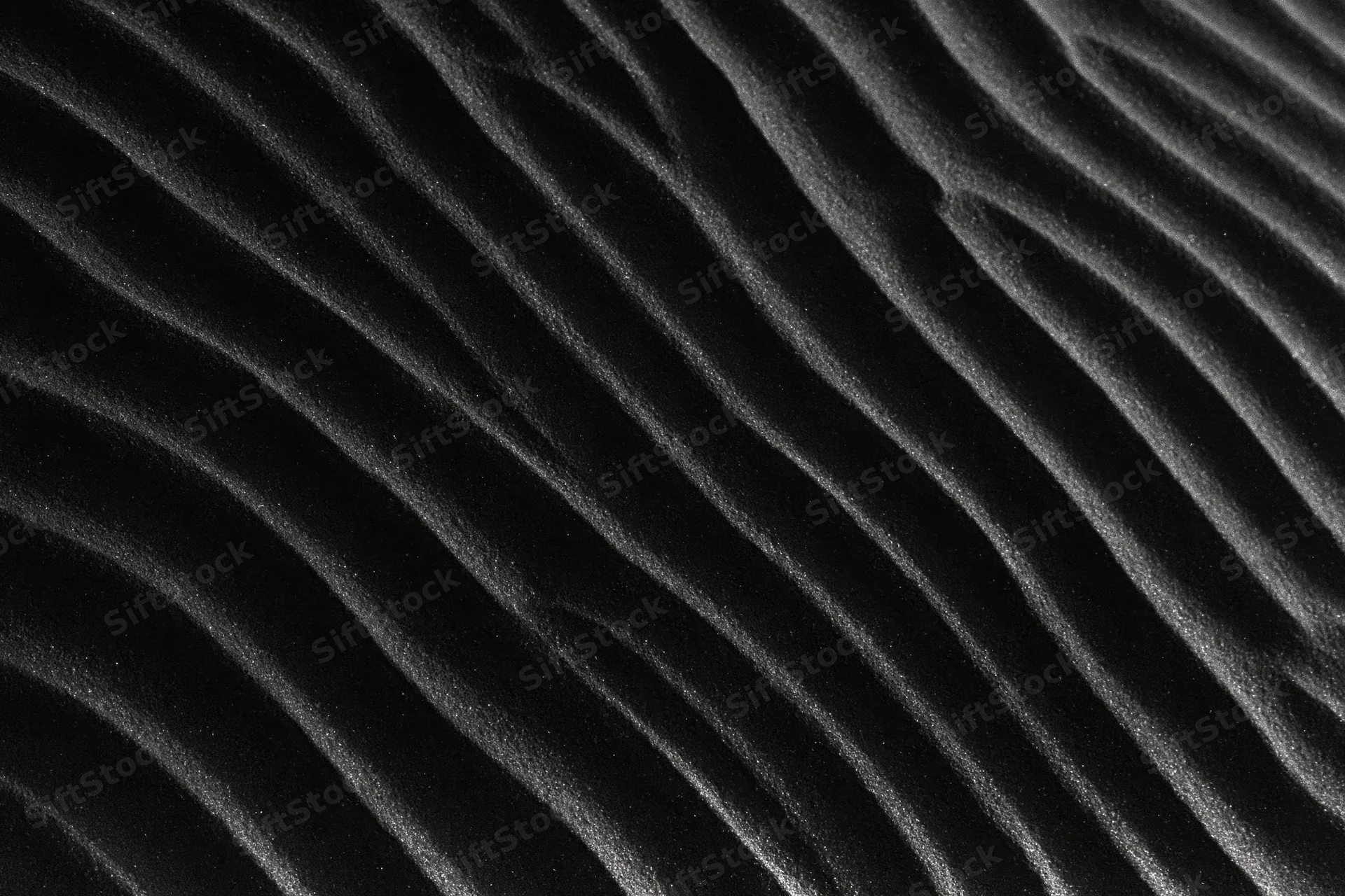 Close-up of rippled black volcanic sand dunes formed by wind erosion