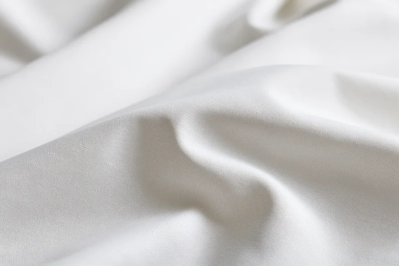 Close-up of smooth white fabric with soft diagonal folds and gentle undulations