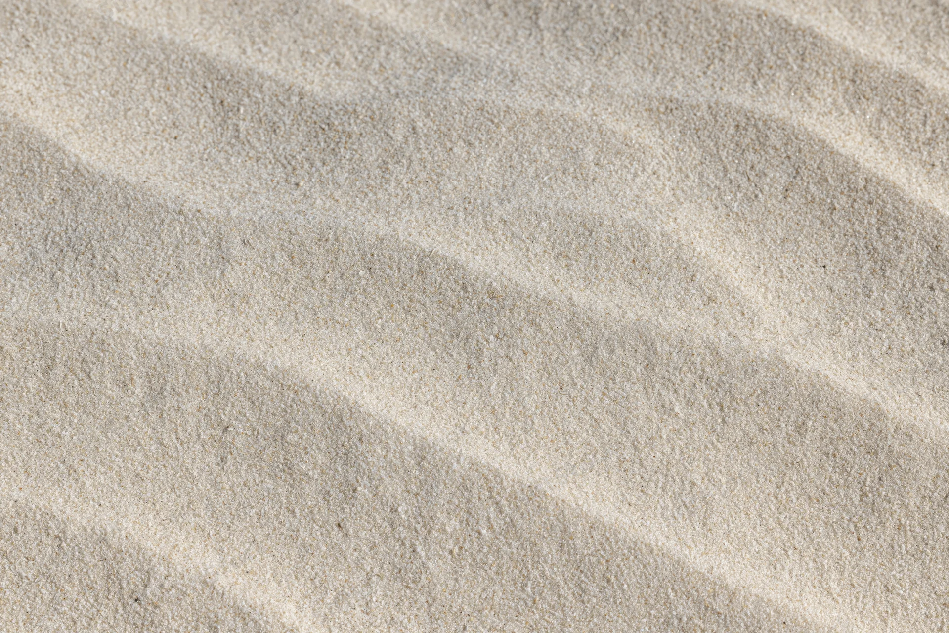 Close-up overhead view of smooth dry beach sand with rippled texture filling the frame