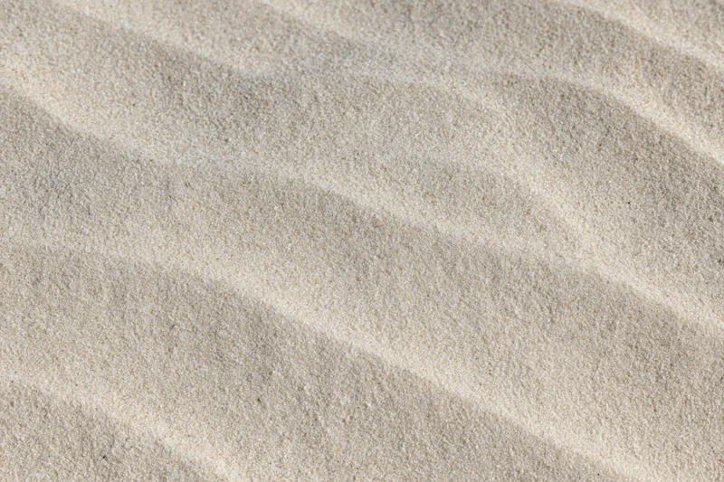 Close-up overhead view of smooth dry beach sand with rippled texture filling the frame