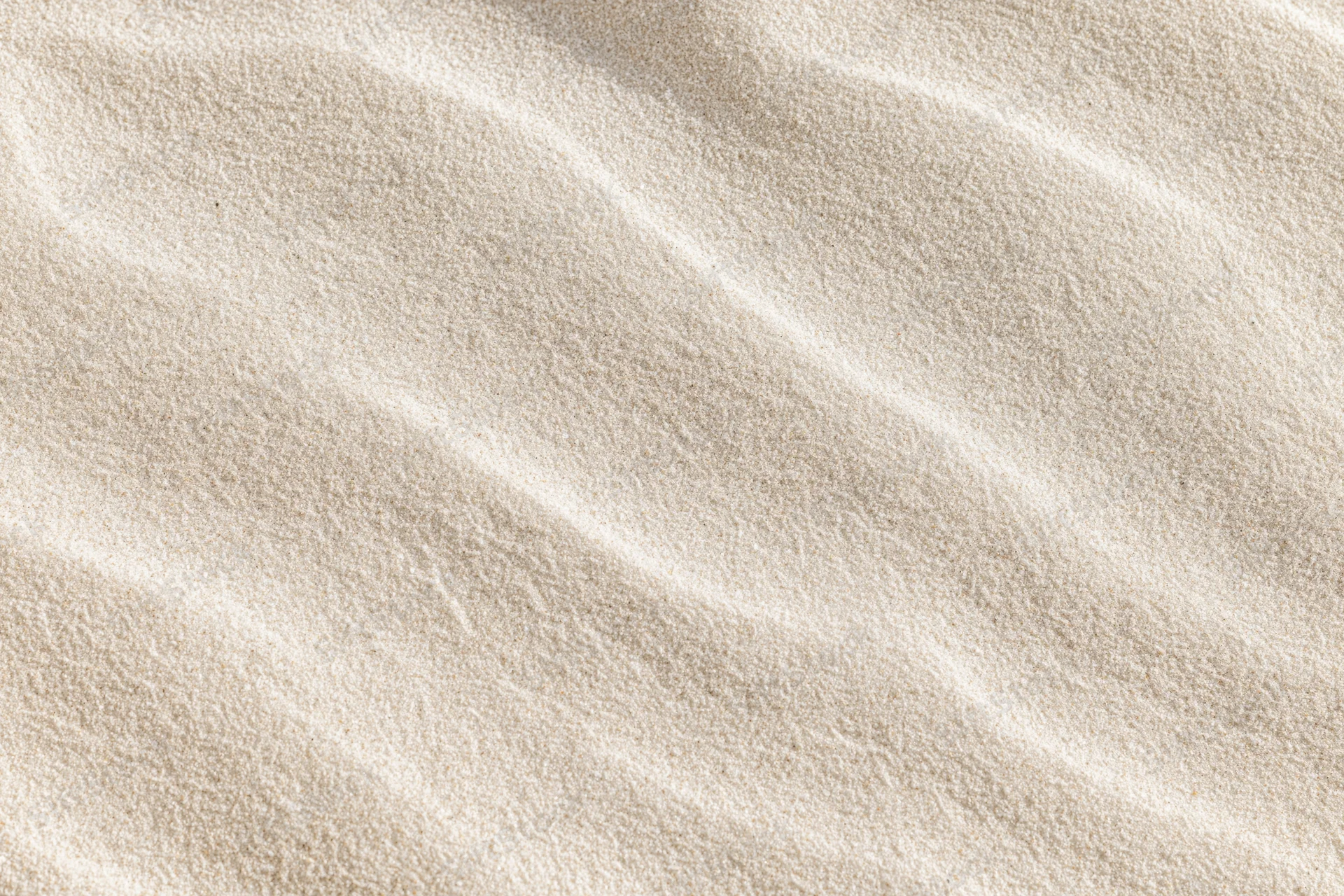 Close-up overhead view of smooth dry beach sand with rippled texture filling the frame