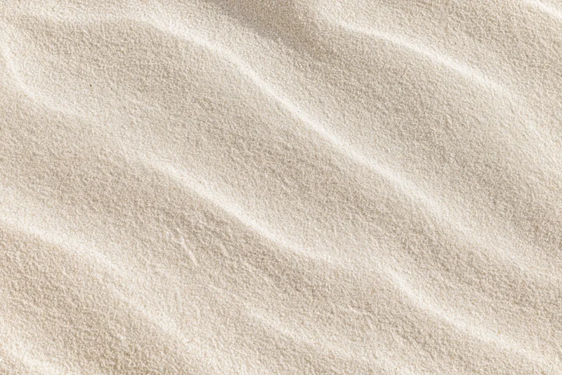 Close-up overhead view of smooth dry beach sand with rippled texture filling the frame