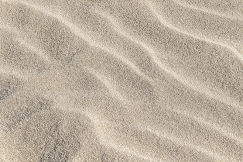 Close-up overhead view of smooth dry beach sand with rippled texture filling the frame