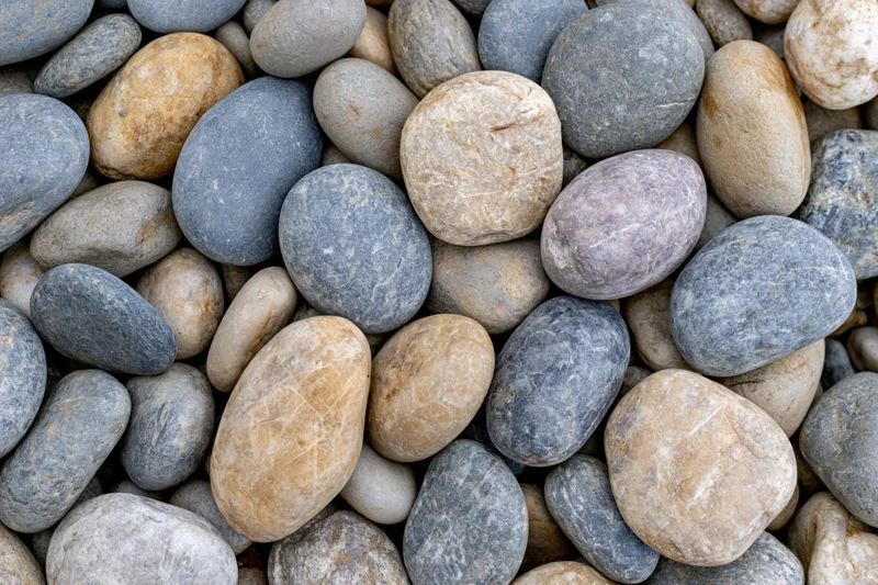 Smooth rounded river pebbles arranged in a dense overhead flat lay pattern