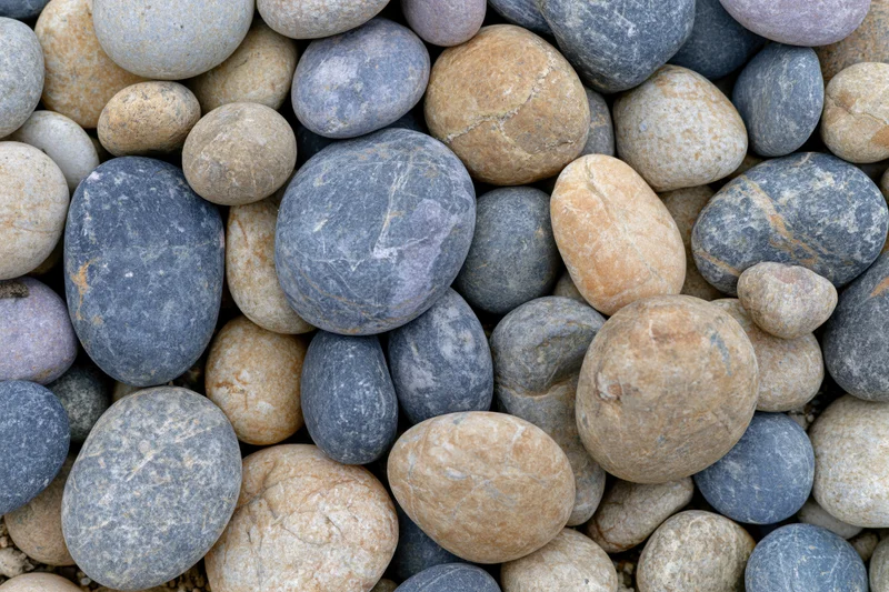 Close-up overhead view of smooth rounded river pebbles arranged in a dense pile
