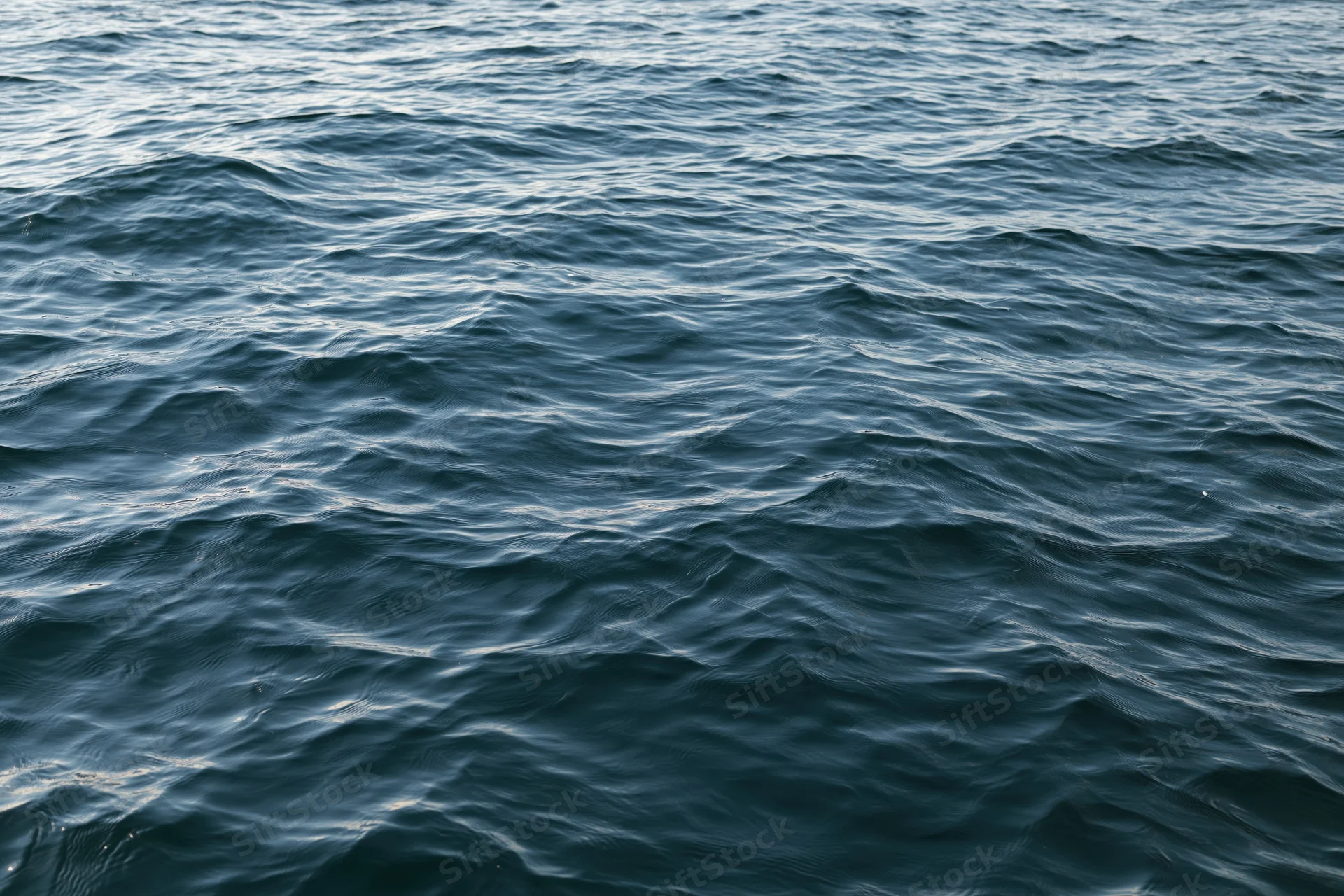 Close-up overhead view of calm ocean water surface with gentle waves and ripples