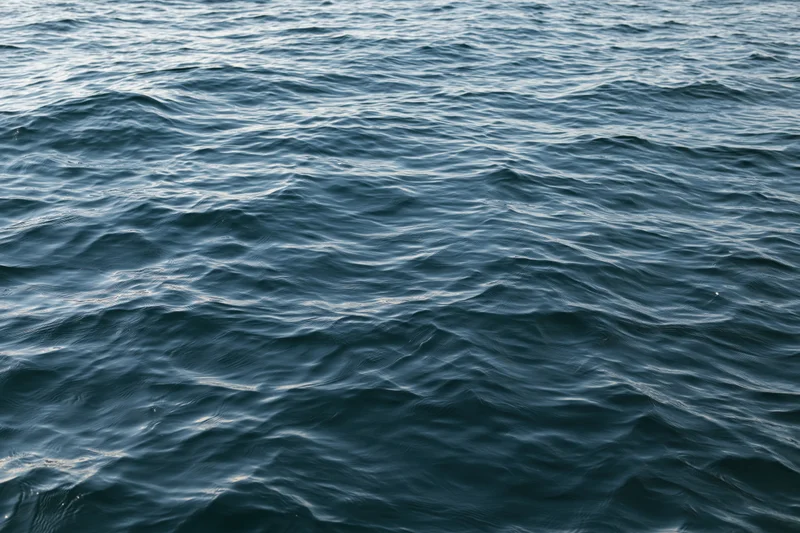 Close-up overhead view of calm ocean water surface with gentle waves and ripples