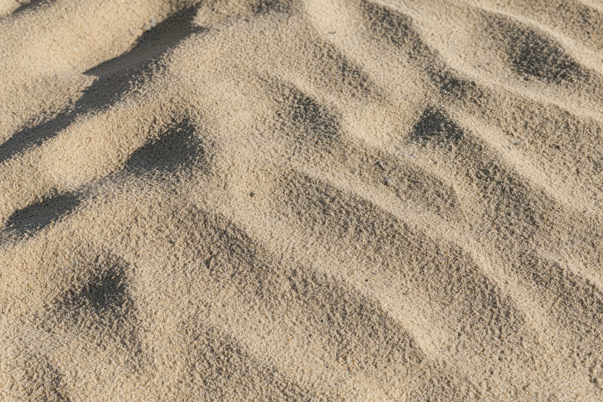 Closeup overhead view of dry beach sand surface with ripples and shadows