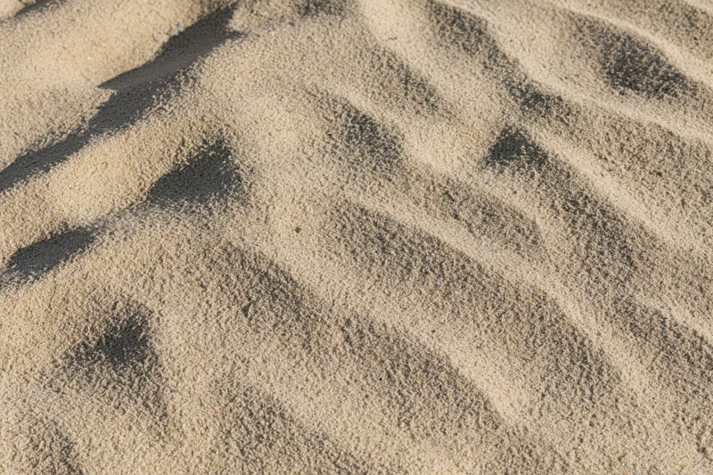 Closeup overhead view of dry beach sand surface with ripples and shadows