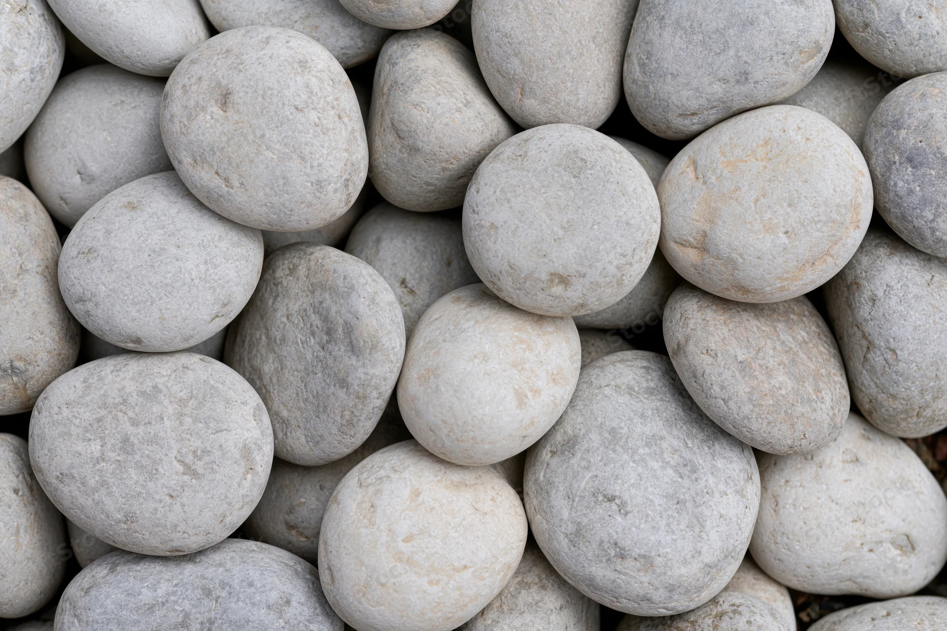 Close-up overhead view of smooth rounded river pebbles packed together in a pile