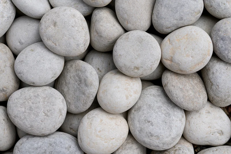 Close-up overhead view of smooth rounded river pebbles packed together in a pile