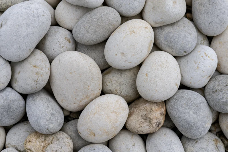 Smooth rounded river pebbles packed together in a close-up overhead view