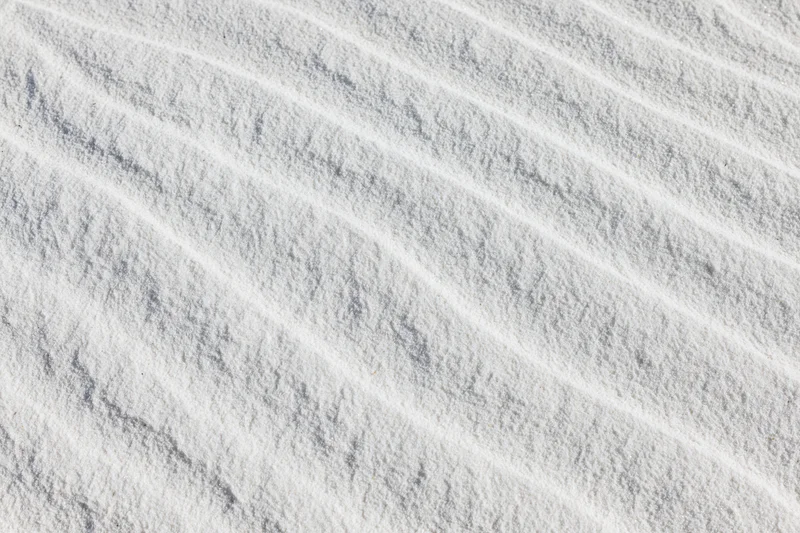 Close-up overhead view of white sand with wind-formed ripples across the surface
