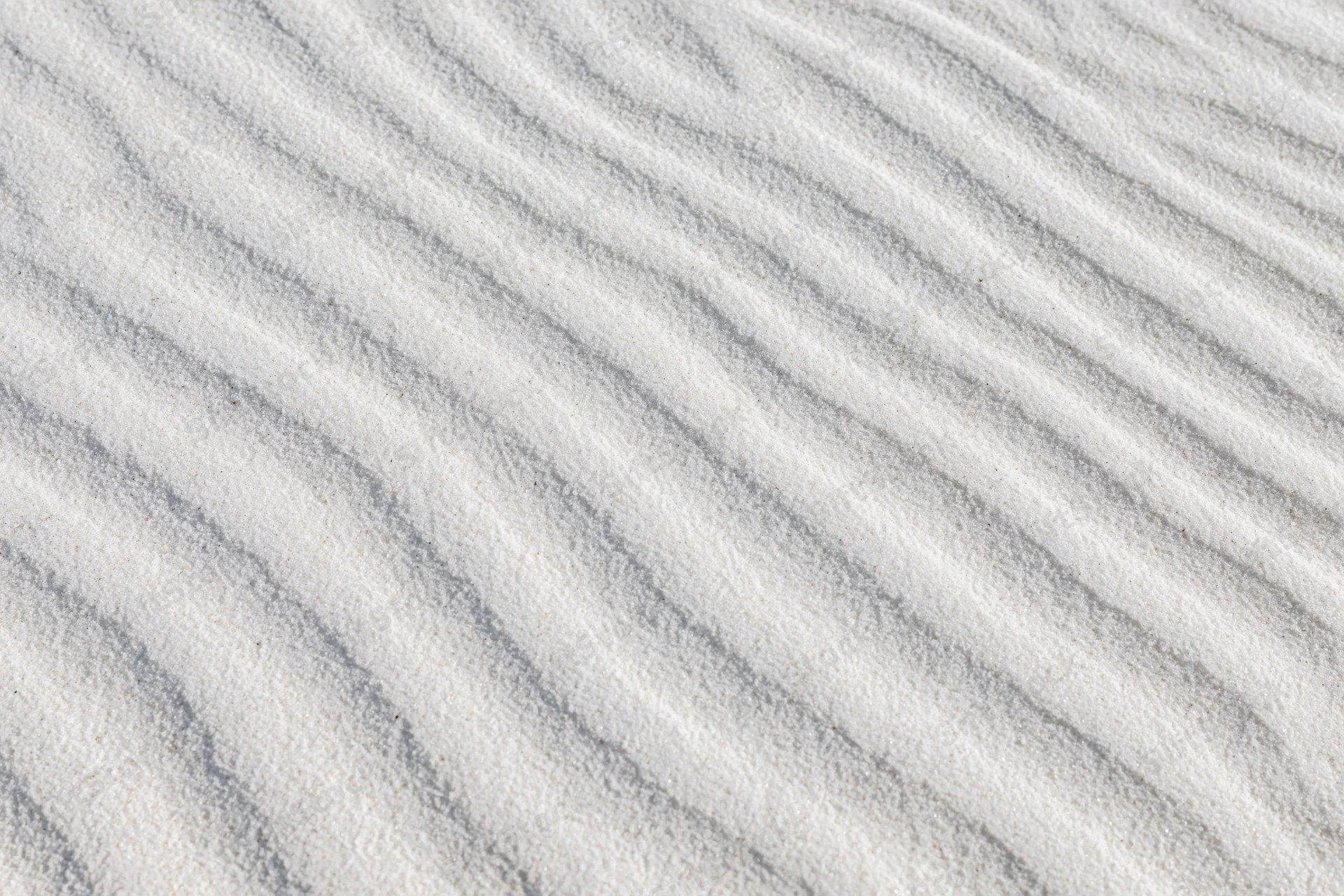 Close-up overhead view of white sand with wind-formed ripples across the surface