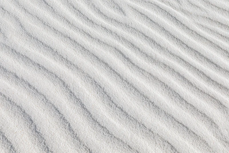 Close-up overhead view of white sand with wind-formed ripples across the surface