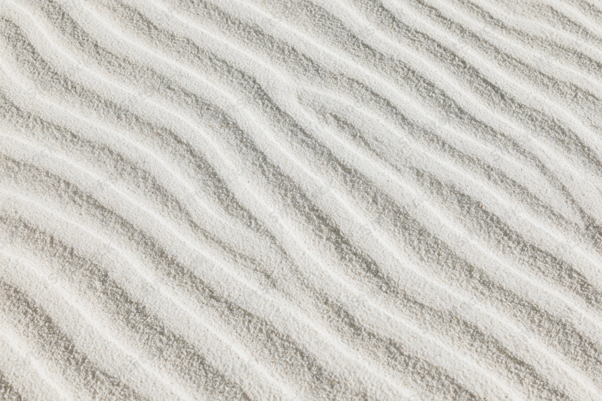 Close-up overhead view of white sand with wind-formed ripple patterns