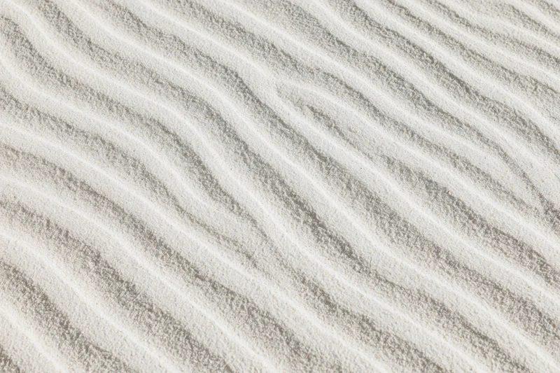 Close-up overhead view of white sand with wind-formed ripple patterns