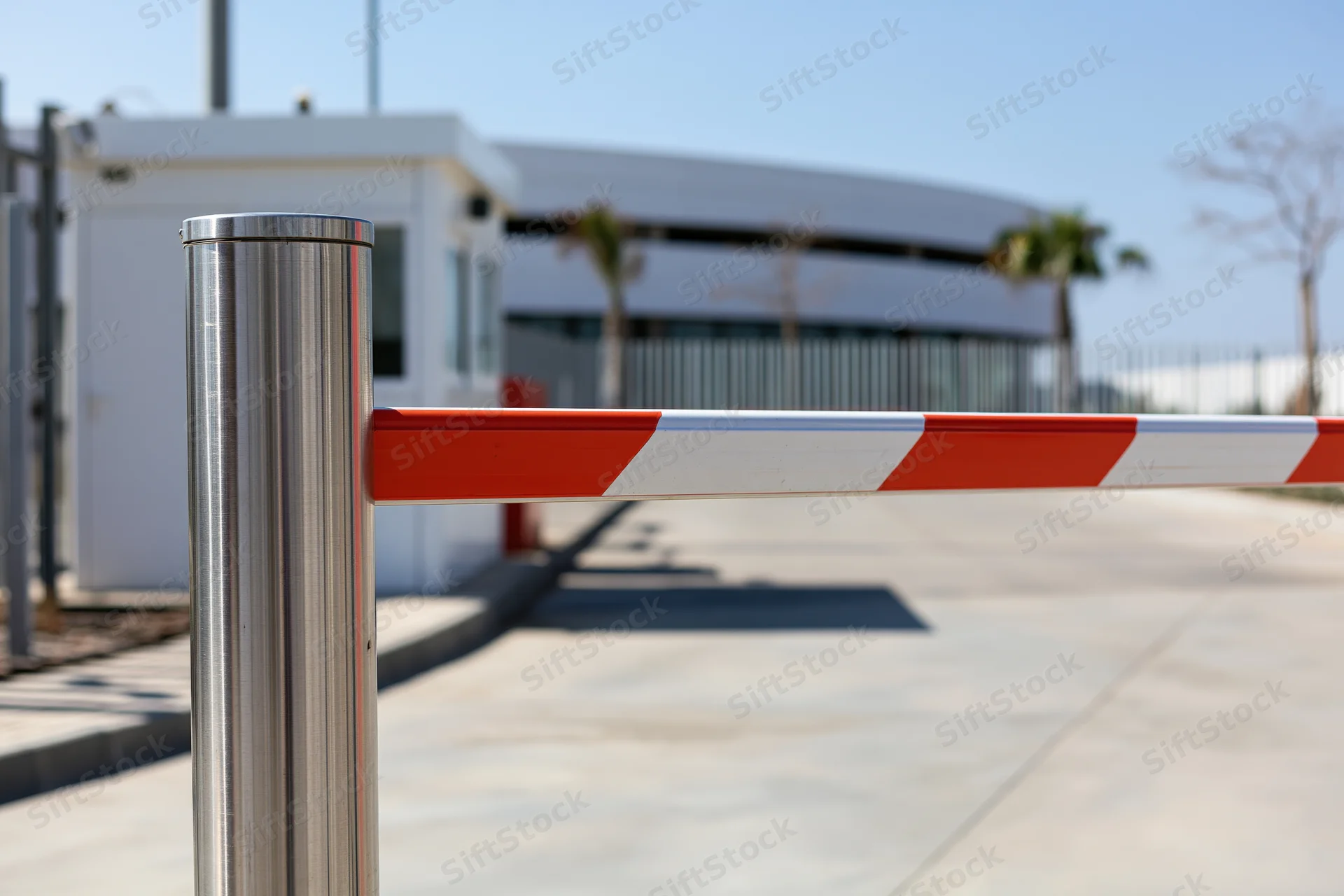 Closed red and white striped boom barrier gate at industrial facility entrance