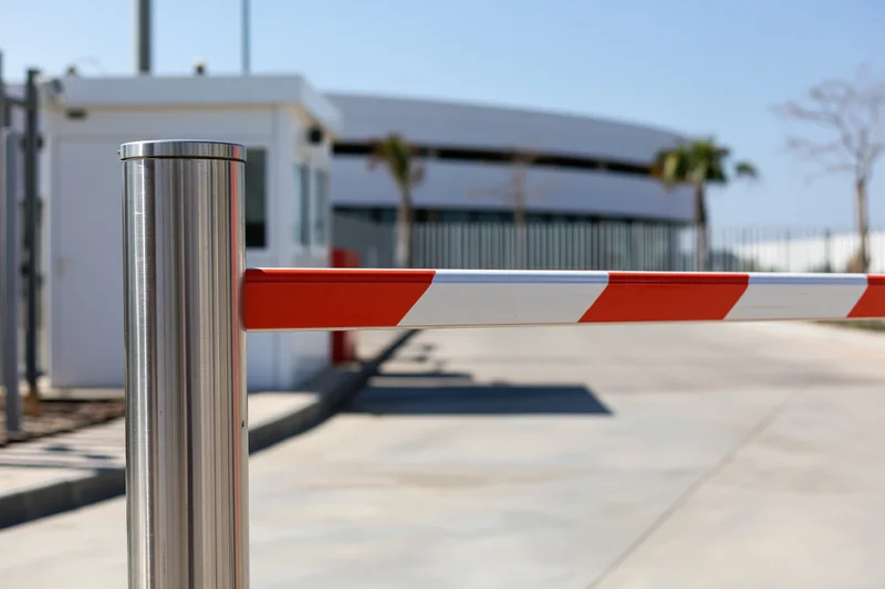 Closed red and white striped boom barrier gate at industrial facility entrance
