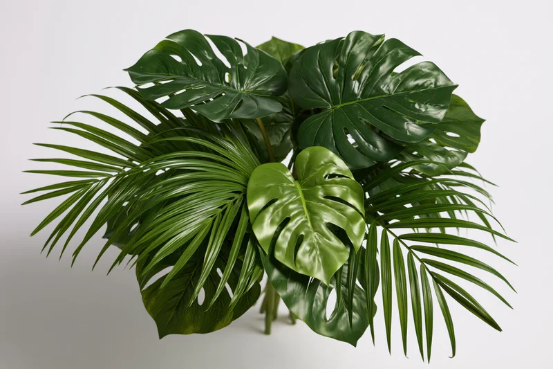 Cluster of monstera and palm leaves arranged in a loose bouquet against a white background