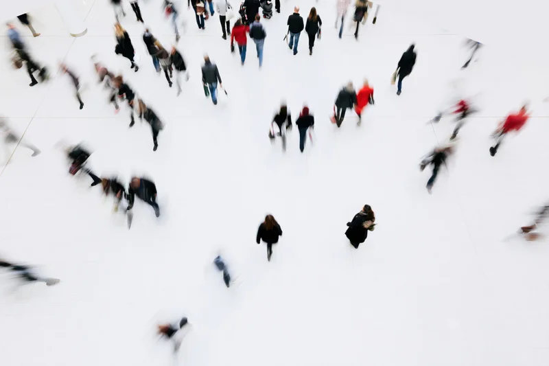 Shoppers moving across a large white atrium in an indoor mall