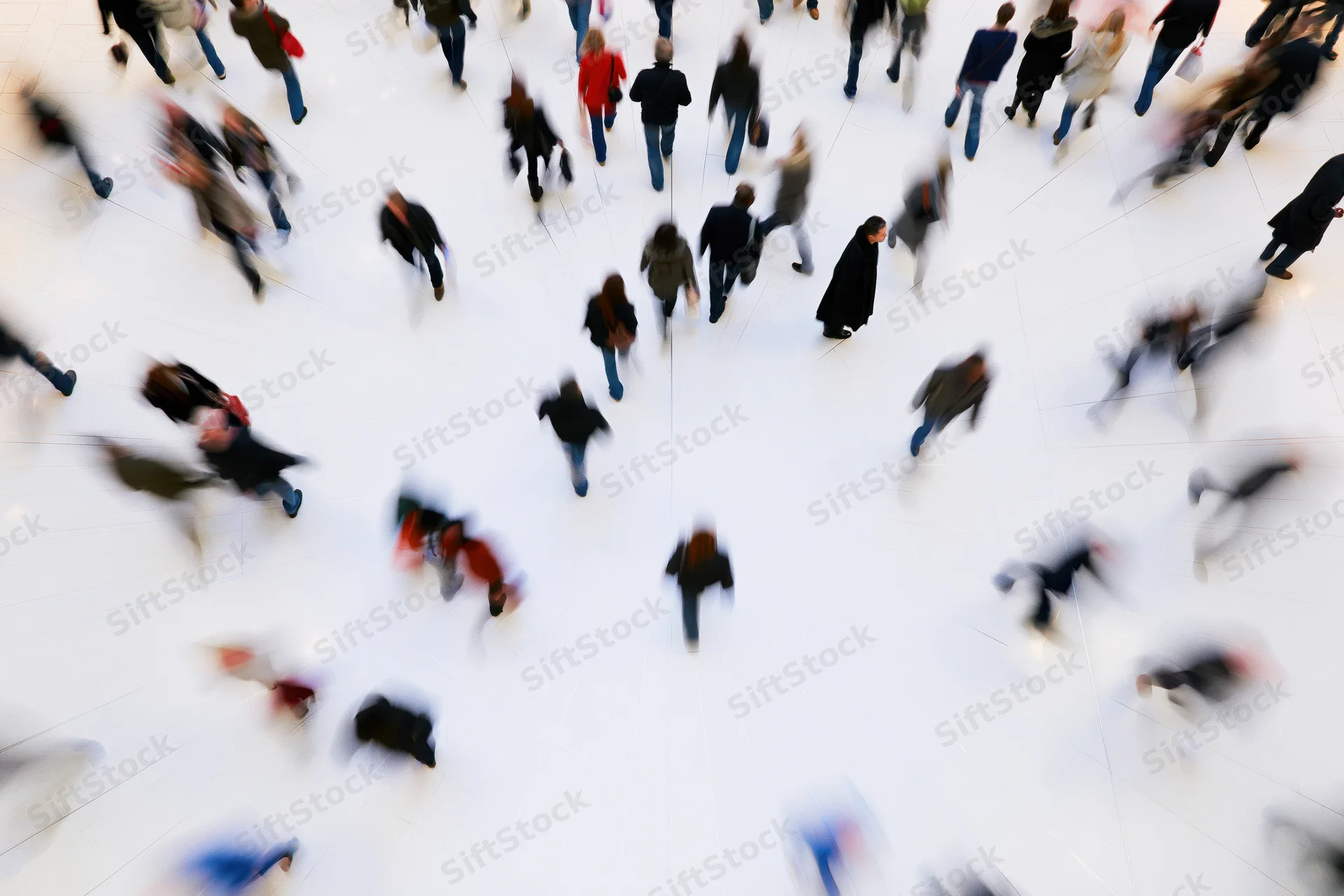 Shoppers walking across a large indoor mall atrium with motion blur