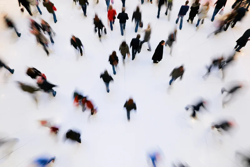 Shoppers walking across a large indoor mall atrium with motion blur