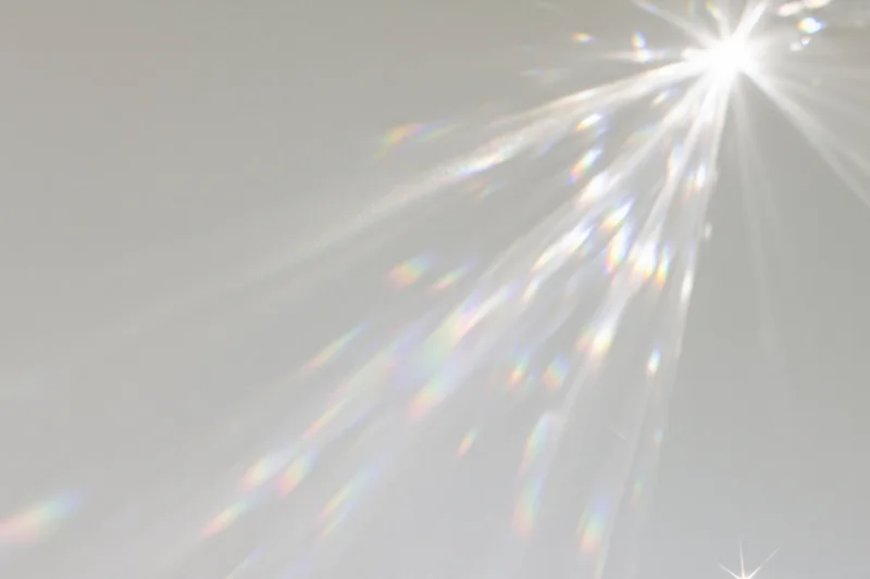 Crystal light refraction patterns cast across a plain matte white surface