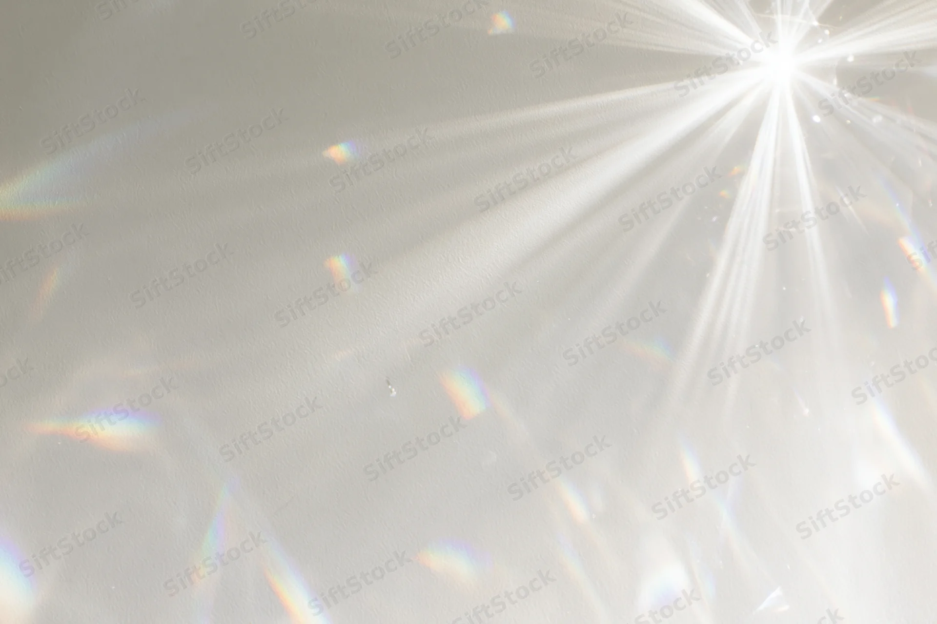 Light refraction patterns from a crystal casting rainbow beams across a matte gray surface