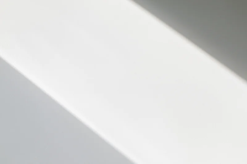 Diagonal band of natural light across a plain white surface