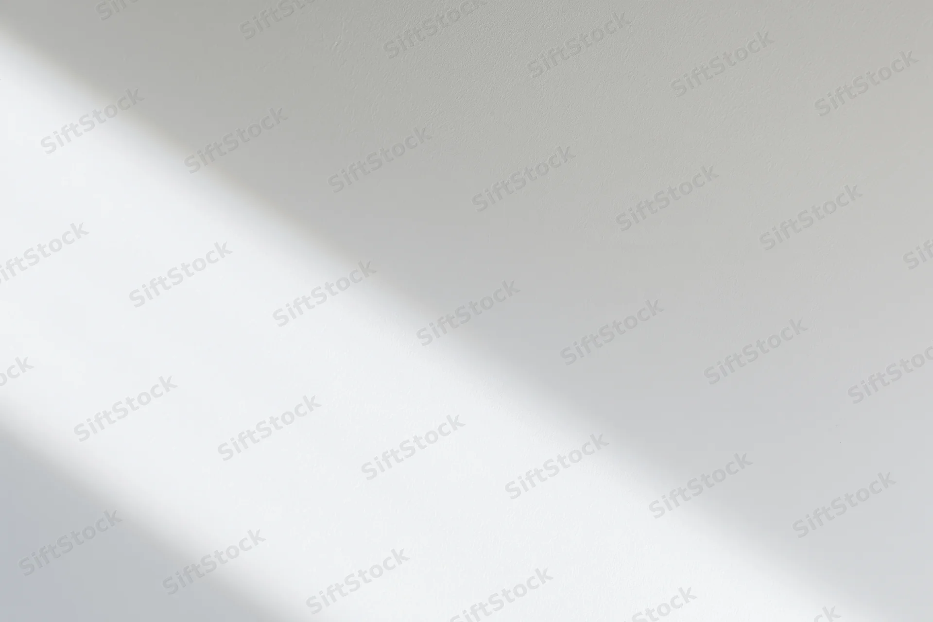 Diagonal band of natural light across a plain white interior surface
